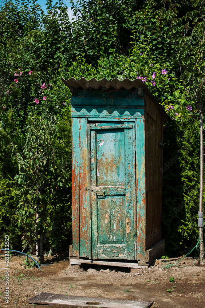 Rustic outdoor toilet stands in the garden sparkling, reflecting the sunshine light Rustic outdoor toilet stands in the garden sparkling, reflecting the sunshine light