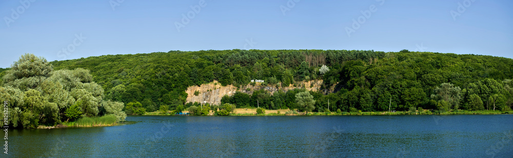 Southern Bug River. District of the Sabarov hydroelectric station. Rock overgrown with dense forest. The inscription on the rock reads 