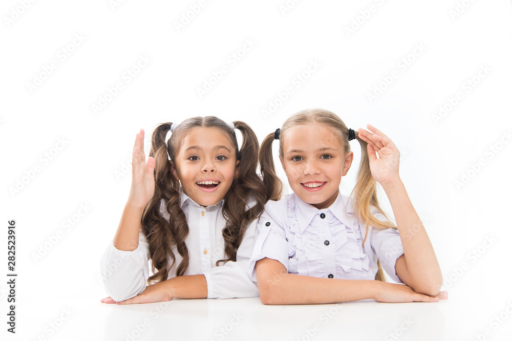 Schoolgirls sit at desk white background. Schoolgirls emotional friends. Back to school. Education concept. Beautiful girls best friends. Adorable schoolgirls. Formal style. Happy childhood