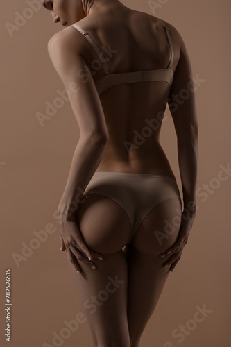 Skinny young woman in lingerie raises her buttocks with her hands