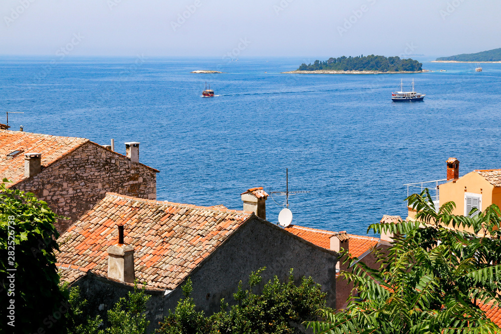 View across the red roofed buildings of the old town of Rovinj, Croatia with the islands of Figarola and Figarolica in the distance