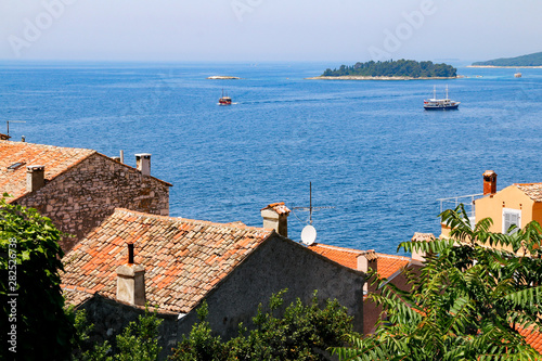 View across the red roofed buildings of the old town of Rovinj, Croatia with the islands of Figarola and Figarolica in the distance photo
