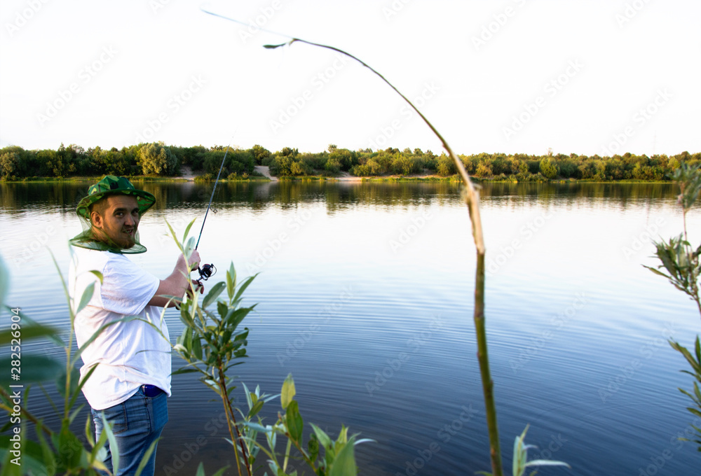 man catches a fish spinning on the background of water in the summer. Russian fishing man catches a fish spinning on the background of water in the summer. Russian fishing