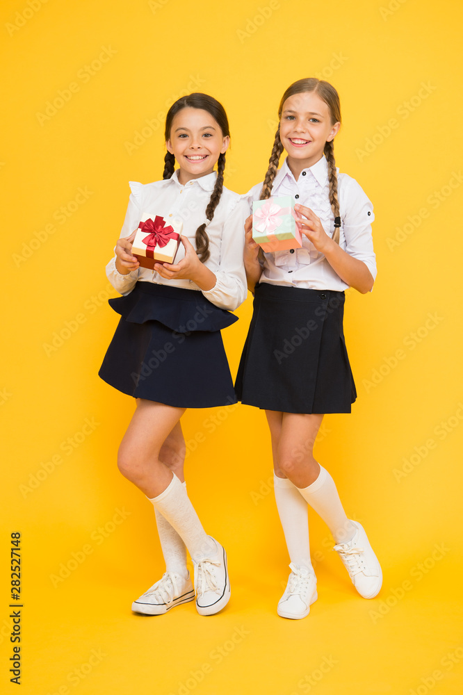 Gift shop. Happy small children holding gifts on yellow background. Little girls smiling with gift boxes. Adorable kids with beautifully wrapped birthday or school gift packs Gift shop. Happy small children holding gifts on yellow background. Little girls smiling with gift boxes. Adorable kids with beautifully wrapped birthday or school gift packs