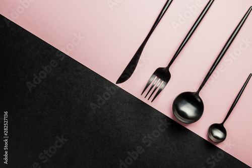 Black setting: plates, inen napkin and silverware on pink and black background. Top view. photo