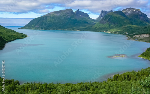 The Fjords Of Norway. Rocky coast. Sunny day, in the distance you can see the village.
