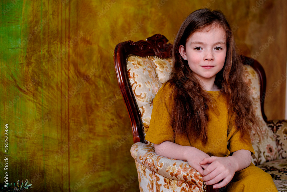 Portrait of little girl sitting on lounge chair Stock Photo | Adobe Stock