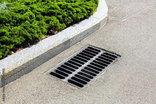 drainage grate on the edge of the curve of the asphalt road. photo