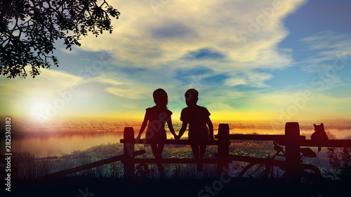 Boy and girl hold hands against the backdrop of summer sunset on the river