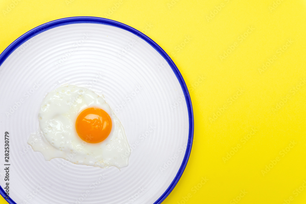 Fried eggs minimal concept on a bright yellow background. Egg yolk on a pan Fried eggs minimal concept on a bright yellow background. Egg yolk on a pan