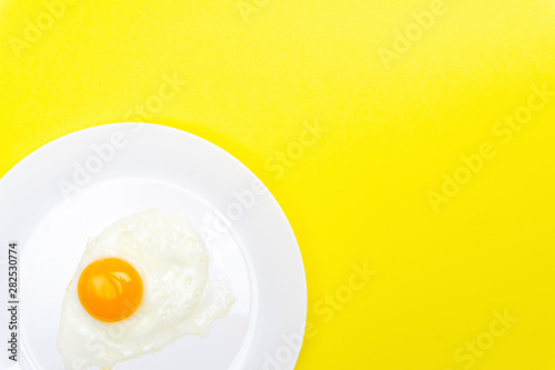 Fried eggs minimal concept on a bright yellow background. Egg yolk on a pan