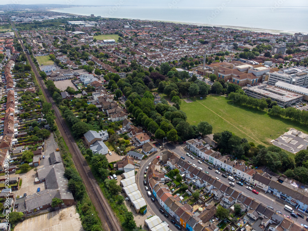 Fototapeta premium Aerial photo of the town of Worthing, large seaside town in England, and district with borough status in West Sussex, England UK, showing typical housing estates and businesses on a bright sunny day