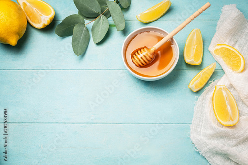 Honey, lemon slices and eucalyptus leaves. Top view image frame from ingredients, copy space, blue background.