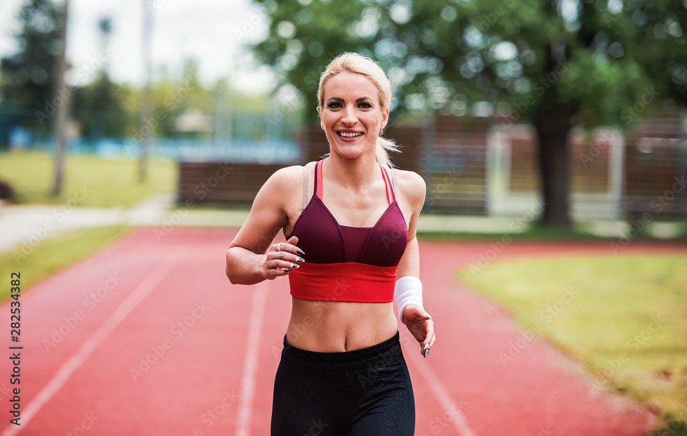 Jogging. Young sportswoman running on athletic track. Sport, fitness, recreation concept Jogging. Young sportswoman running on athletic track. Sport, fitness, recreation concept