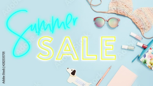 Summer sale neon sign text flickering on blue fashion and beauty product  flat lay background