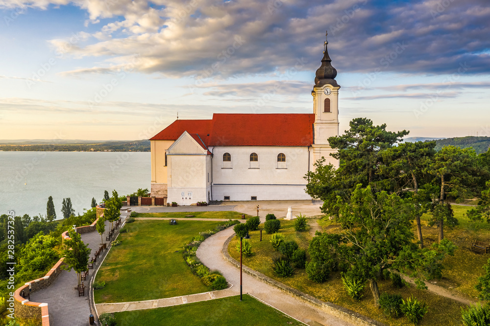 Naklejka premium Tihany, Hungary - Aerial view of the famous Benedictine Monastery of Tihany (Tihany Abbey) with beautiful golden sunrise clouds over Lake Balaton
