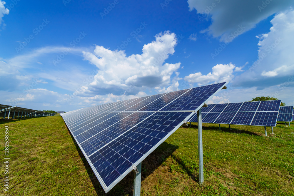 Solar panel on blue sky background. Green grass and cloudy sky. Alternative sun energy concept