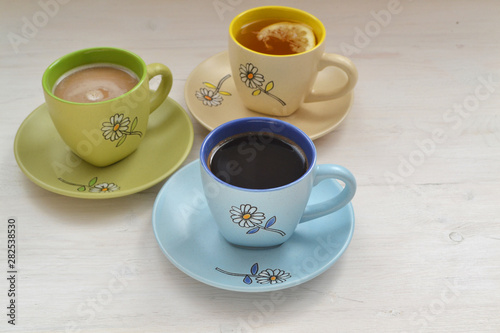 Coffee, cappuccino and Tea in colorful cups  on shabby table