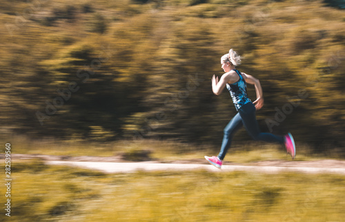 Panning photo of girl wearing sportswear doing fitness activities outdoors.