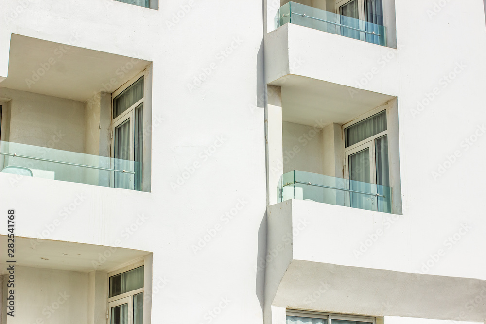 white hotel building exterior facade corner geometric shapes with balcony and window 
