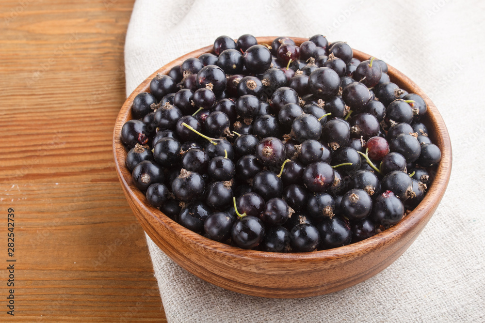 Fresh black currant in wooden bowl on wooden background. side view. Fresh black currant in wooden bowl on wooden background. side view.