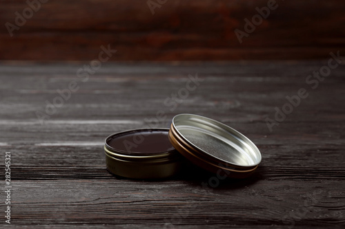 Can of black shoe polish on wooden table. Footwear care item photo