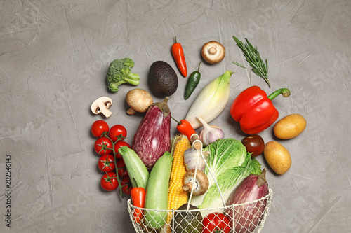 Different vegetables and metal basket on grey background  top view