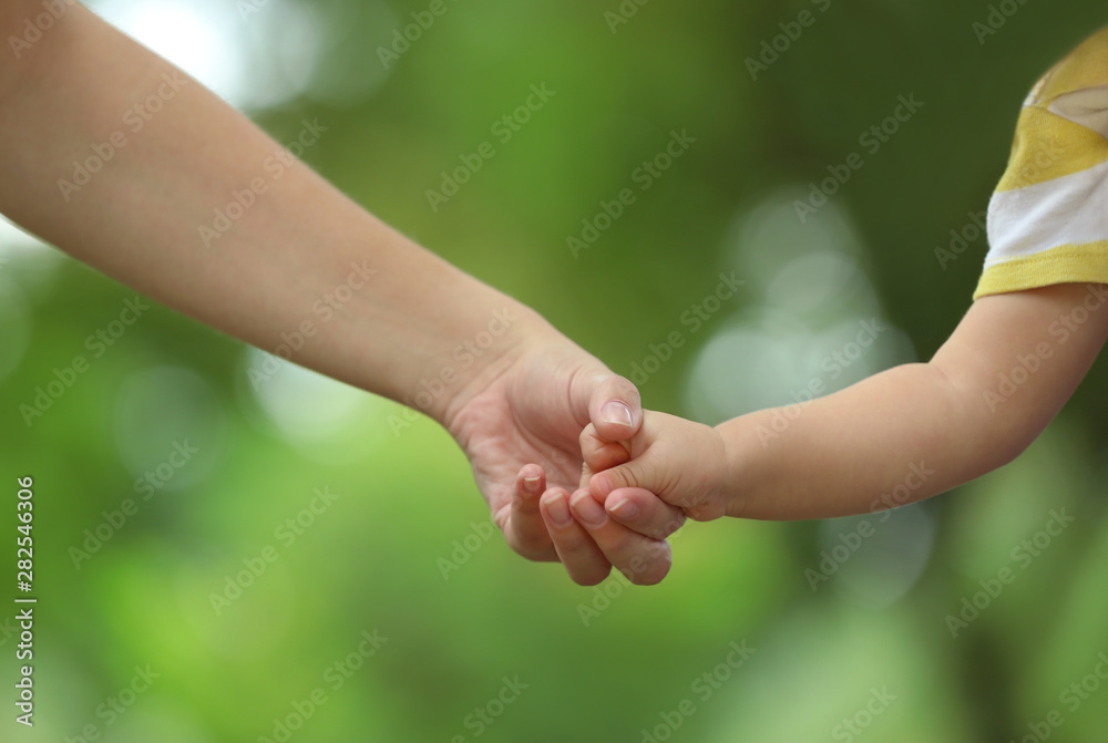 Mother with her baby holding hands together in park on summer day Mother with her baby holding hands together in park on summer day