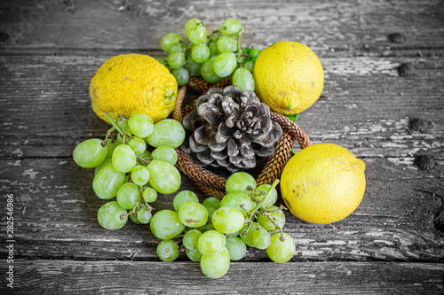 Grapes, lemons and pine cone on wooden background, still life photography