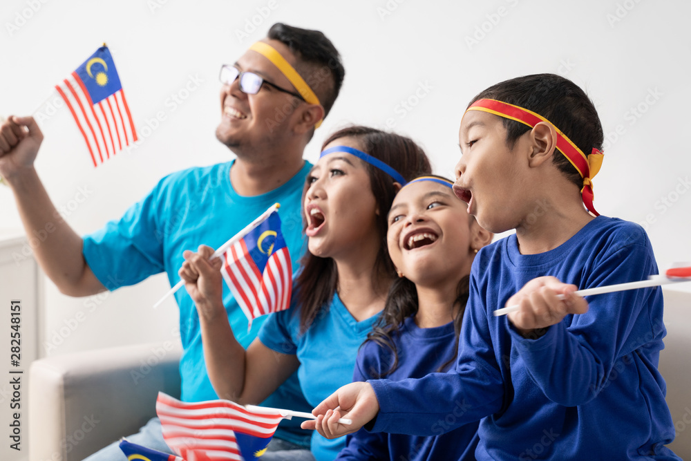 Obraz premium excited malaysian sport fans supporter. asian family with malaysia flag