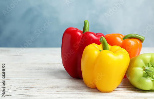 Ripe bell peppers on white wooden table against light blue background  space for text