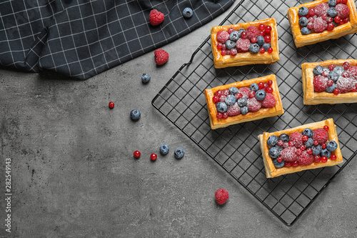 Fresh delicious puff pastry with sweet berries on grey table  flat lay. Space for text