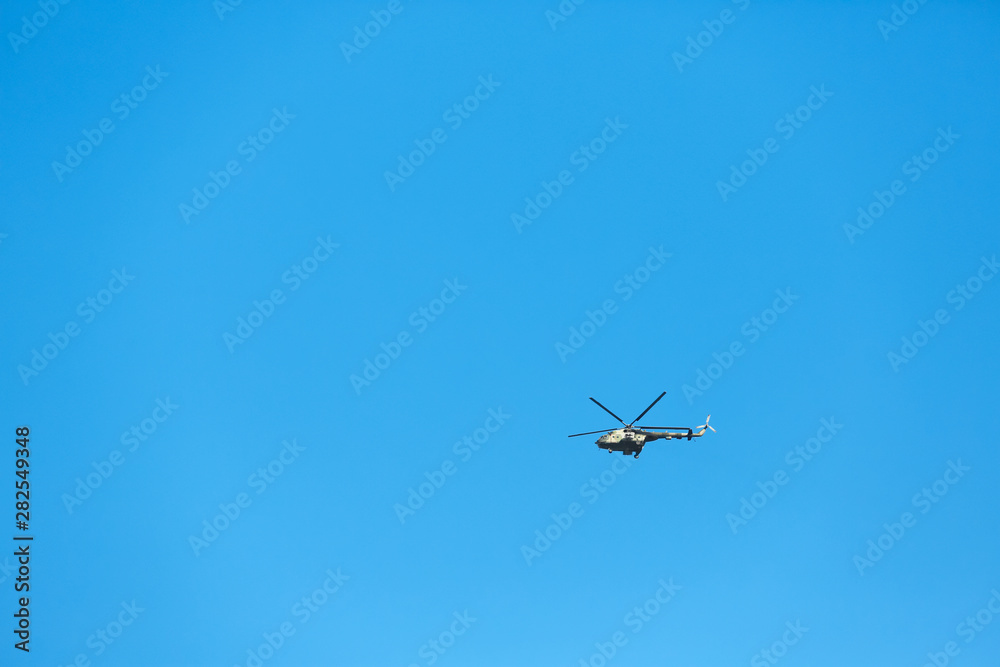 Modern military helicopter flying in blue sky Modern military helicopter flying in blue sky