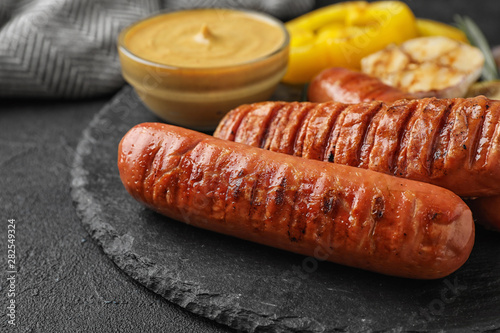 Delicious grilled sausages on black table, closeup. Barbecue food