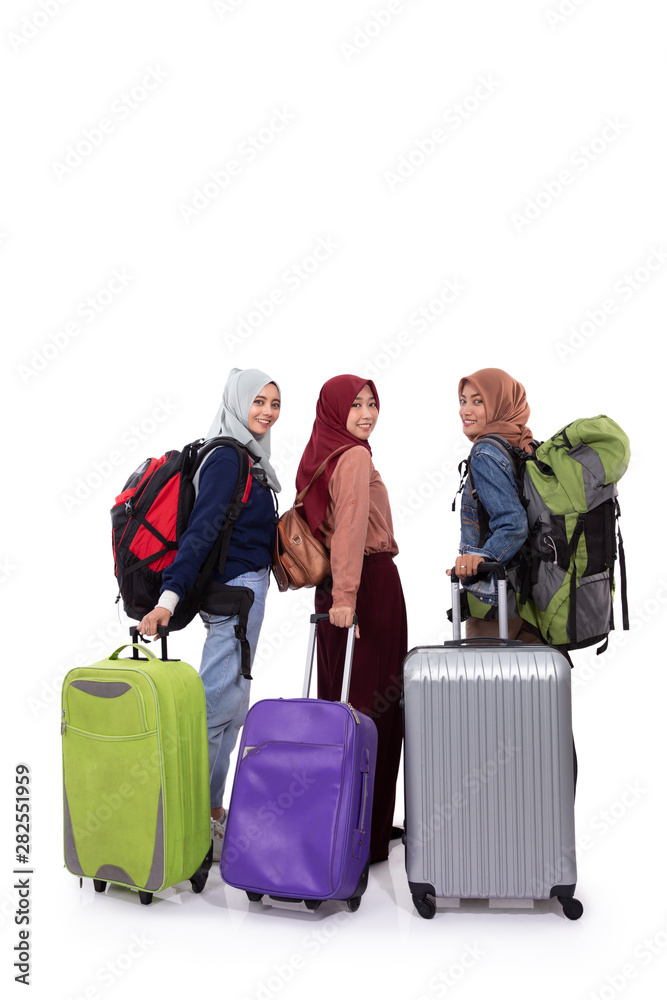 Back view, three hijab woman standing holding suitcase and carrying bag with isolated background Back view, three hijab woman standing holding suitcase and carrying bag with isolated background