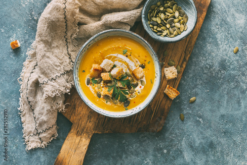Pumpkin soup in a bowl with croutons and pumpkin seeds. Top view.