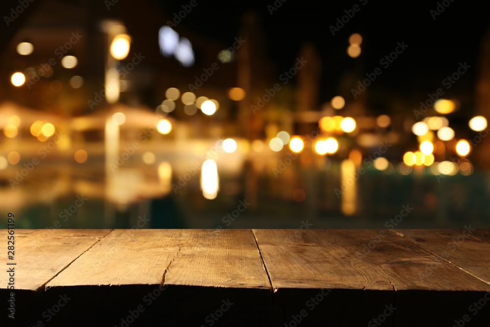 background Image of wooden table in front of abstract blurred restaurant lights