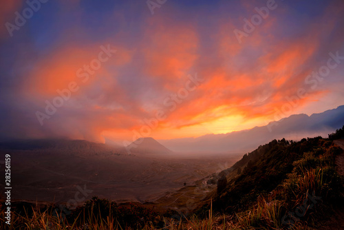 Orange sky glowing at sunset above erupting volcano Mount Bromo one of the best tourist destinations in Java Indonesia