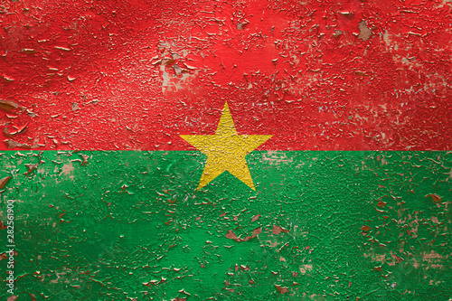 National flag of Burkina Faso on old peeling wall background.The concept of national pride and symbol of the country.