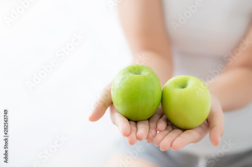 Closeup young asian woman holding and eating green apple fruit in the bedroom at home, lifestyle of nutrition girl healthy and care weight loss, health and wellness concept.