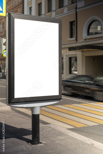 Mock up rectangular vertical lightbox onstreet in city. Advertising construction. Copy space. banner on sidewalk narrow street. Against backdrop building and passing car.