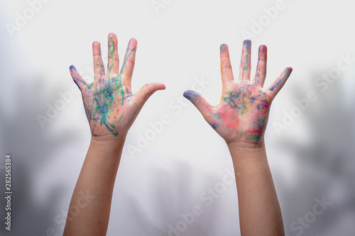 Two hands of girl dirty stained color and hands shadow on white wall background