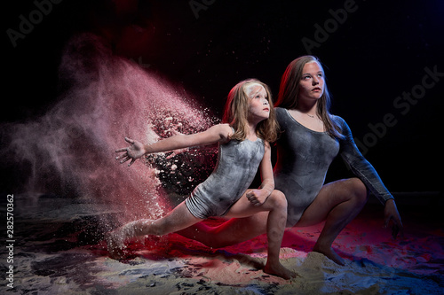 Two sisters in black studo with red and blue light during photoshoot with flour photo