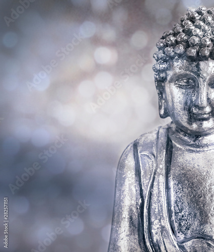 Silver Buddha Statue Across Blurry Background photo