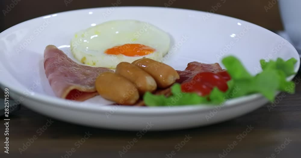 Tilting scene video of a plate of breakfast that has fried egg, sausage, bacon, and lettuce, it look delicious. Tilting scene video of a plate of breakfast that has fried egg, sausage, bacon, and lettuce, it look delicious.