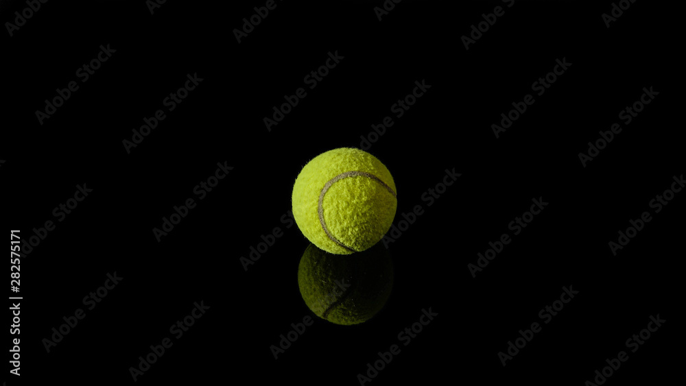 1 one green tennis ball isolated in black with reflection below it