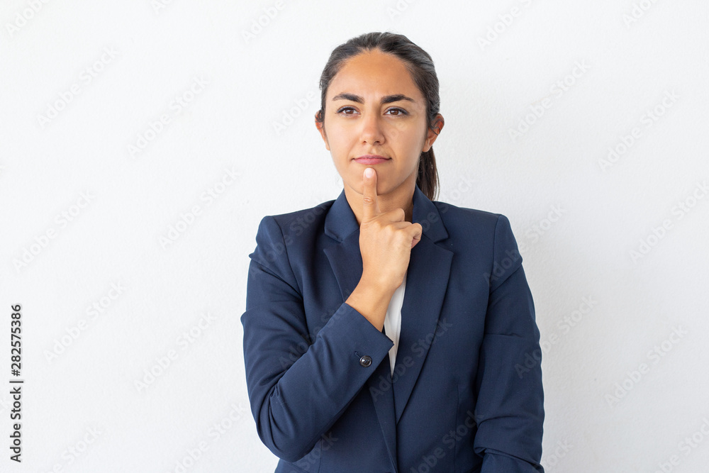 Thoughtful young businesswoman. Portrait of pensive young woman in formal wear holding finger on chin isolated on grey background. Emotion concept Thoughtful young businesswoman. Portrait of pensive young woman in formal wear holding finger on chin isolated on grey background. Emotion concept