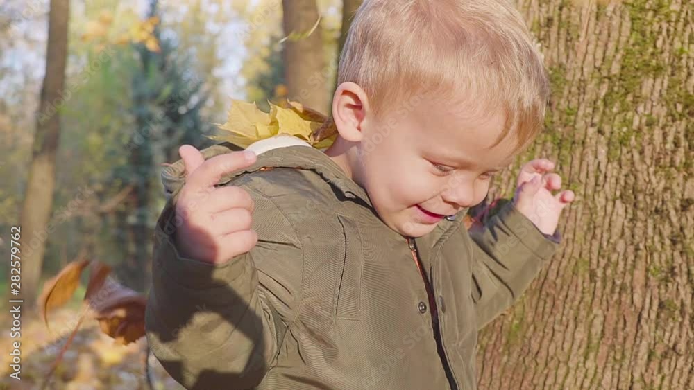 Happy little boy playing with autumn leaves. Game in the park Happy little boy playing with autumn leaves. Game in the park