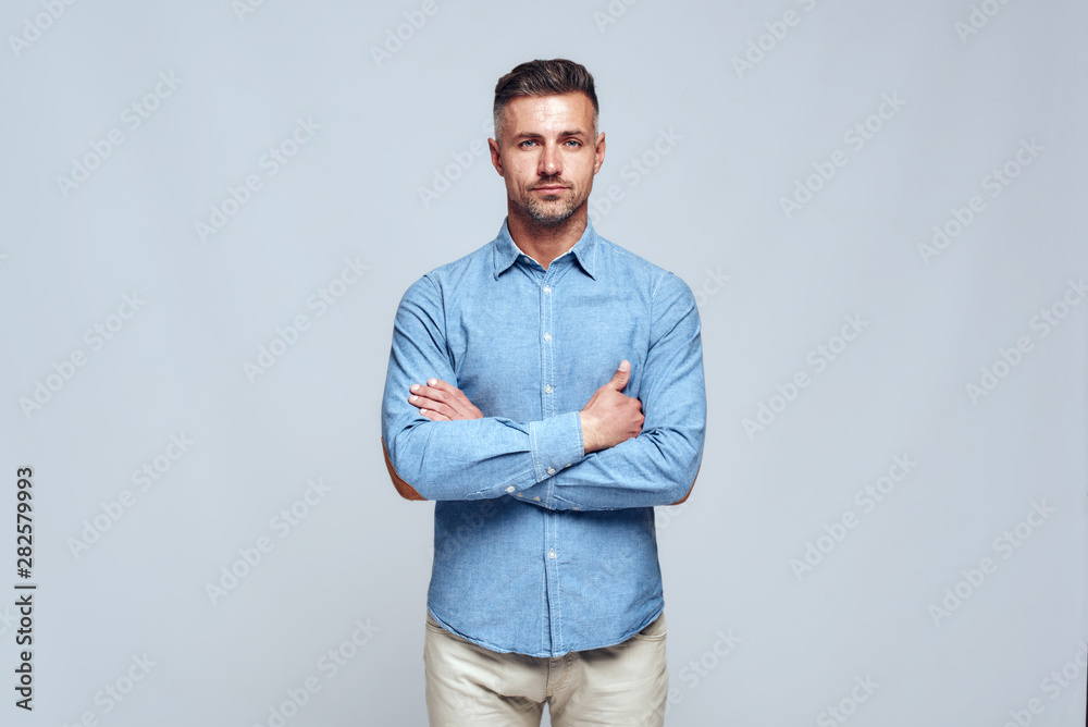 Portrait of young handsome bearded man in casual wear standing with crossed arms and looking at camera Portrait of young handsome bearded man in casual wear standing with crossed arms and looking at camera