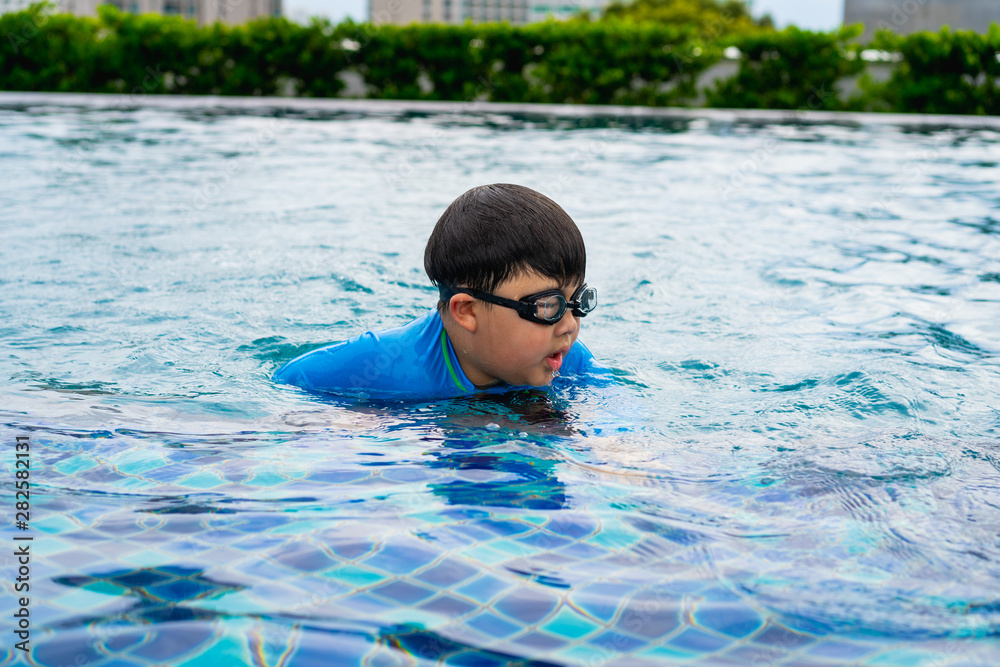 A boy is playing and swimming at the swimming pool in the evening.